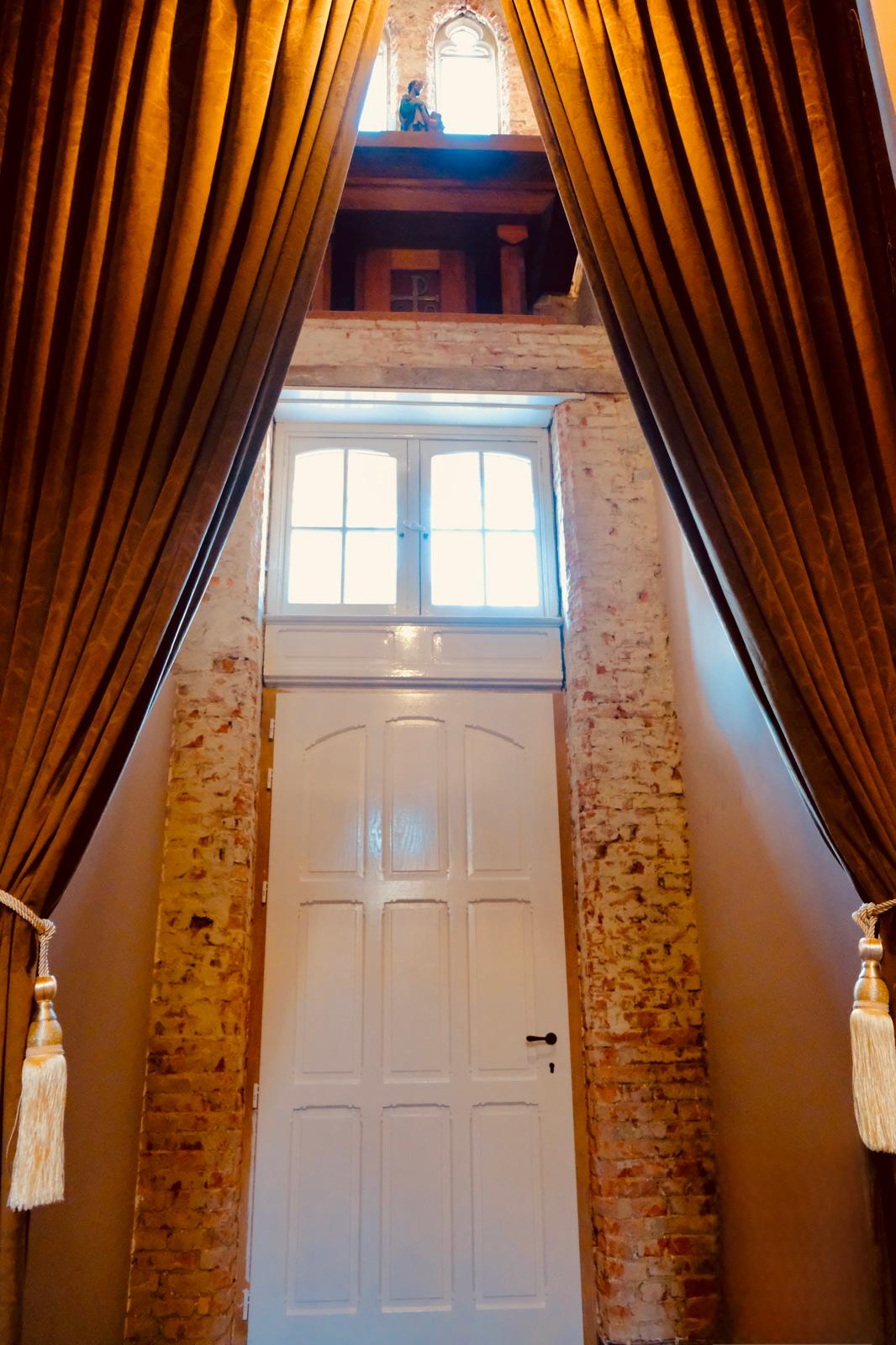 Historische deur met bakstenen muur en fluwelen gordijnen